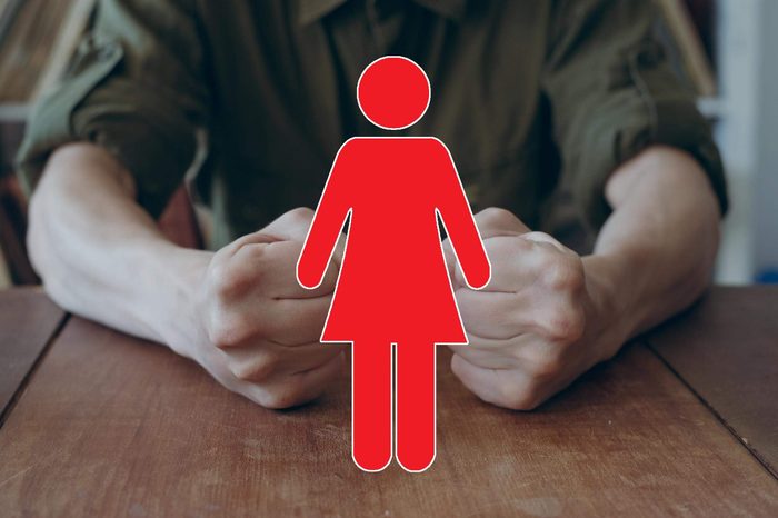 anonymous man seated at a table with his fists on the table with female symbol overlay