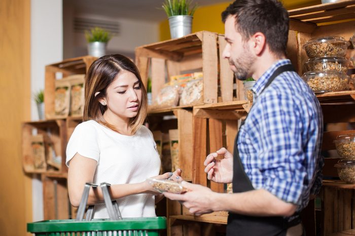 Cute brunette getting some assistance from a store clerk at a local grocery store