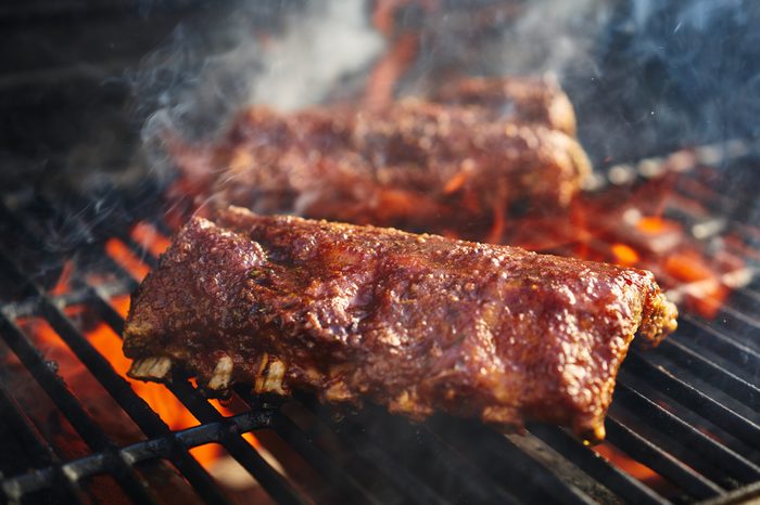 bbq pork ribs cooking on flaming grill shot with selective focus