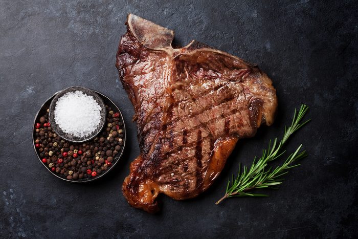 Grilled T-bone steak on stone table. Top view