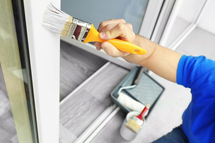 Young man painting window at home, closeup