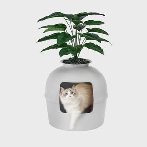 A cat sits in a dome-shaped litter box designed as a planter with green leaves, set against a plain background.