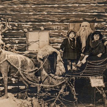 Reindeer stands by sleigh with children and Santa, in front of a log cabin. Sign reads: "Merry Christmas 1935."
