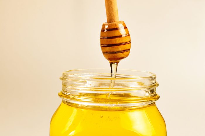 Dipper with honey in woman hand. Space for text or design.