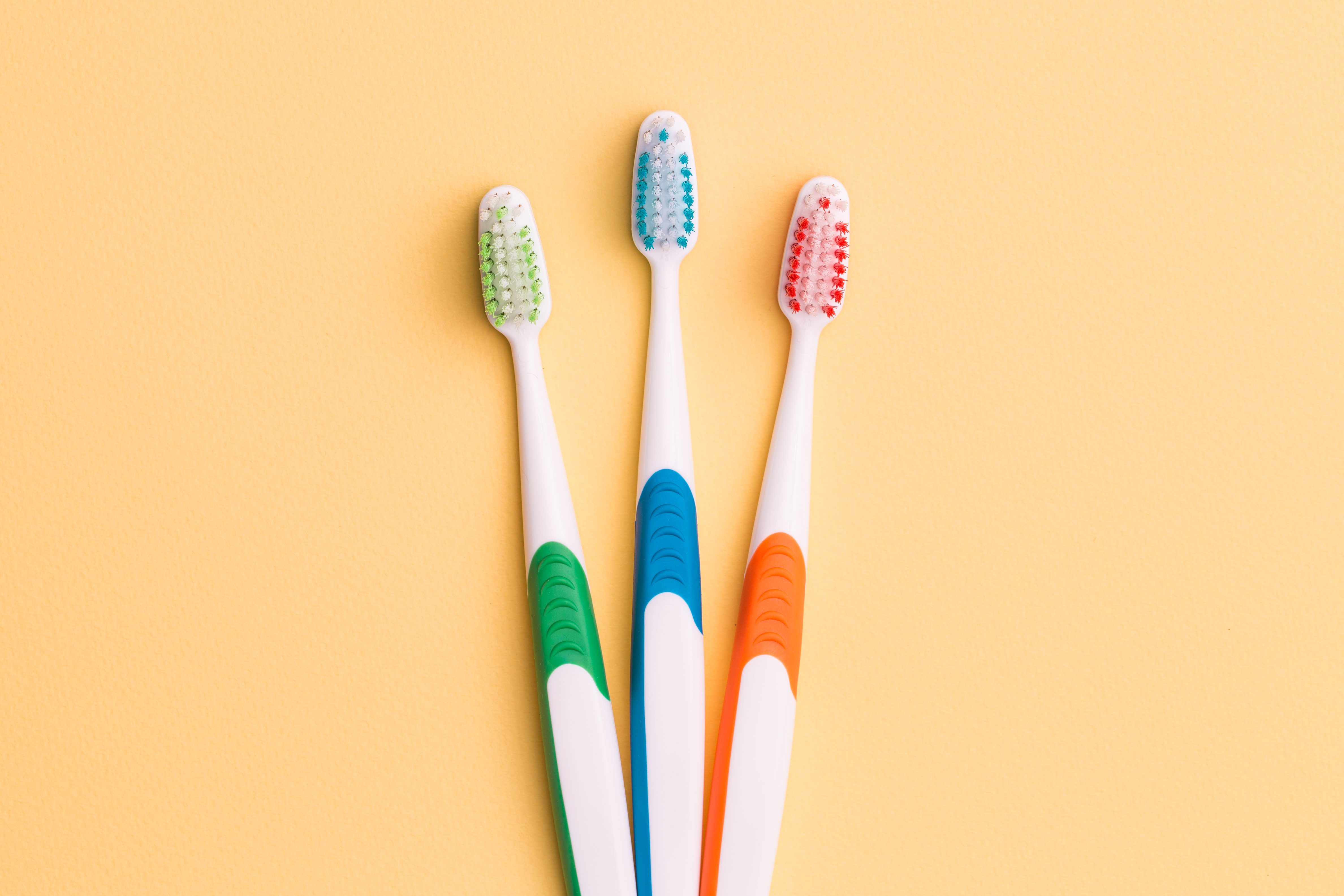 Toothbrushes on empty orange background