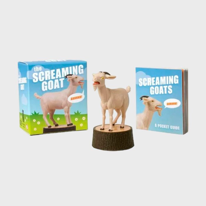 Goat figurine stands on a stump, mouth open, next to a â€œScreaming Goatsâ€ box and pocket guide in a playful, whimsical setup.