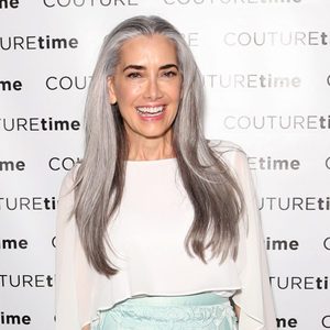 Woman smiling, standing against a patterned backdrop with 