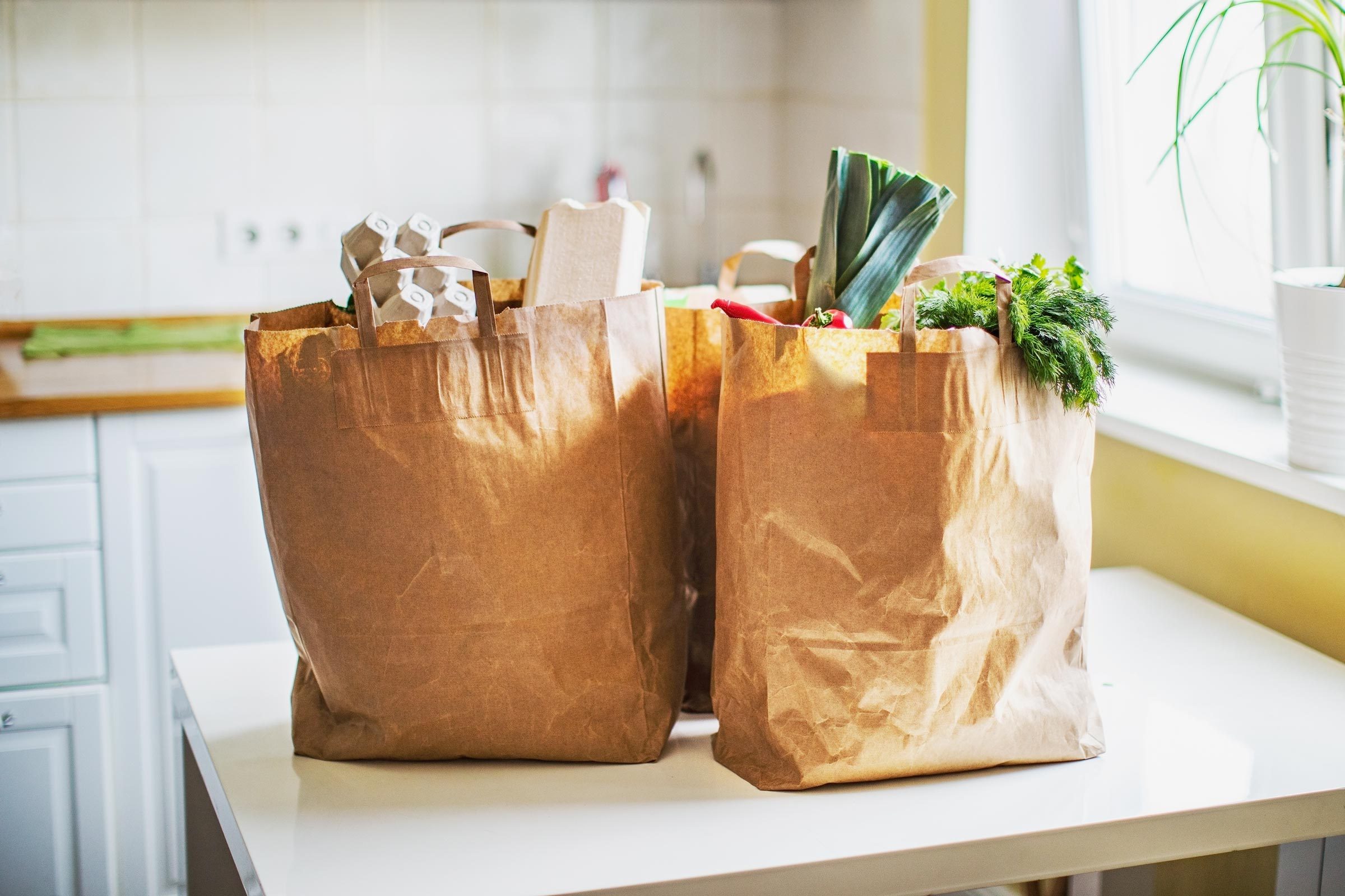 brown paper bags filled with groceries on a kitchen table