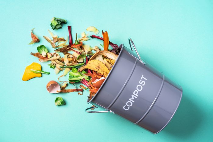 Trash bin for composting with leftover from kitchen on blue background. Top view. Recycling scarps concept. Sustainable and zero waste lifestyle