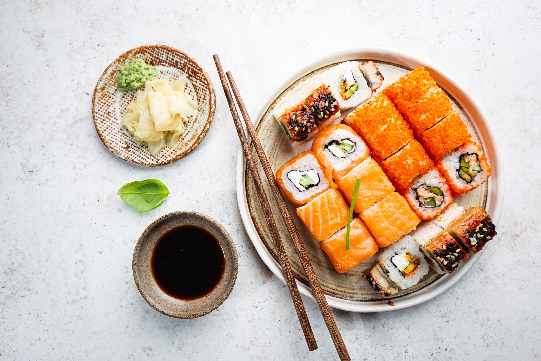 plate with salmon sushi rolls with a side of soy sauce and ginger