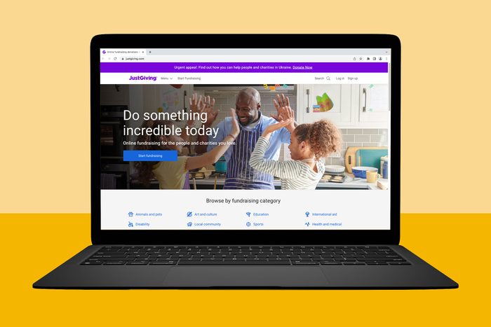 Laptop displays a website showing people high-fiving in a kitchen, promoting online fundraising for charities. Categories include animals, art, education, and more.