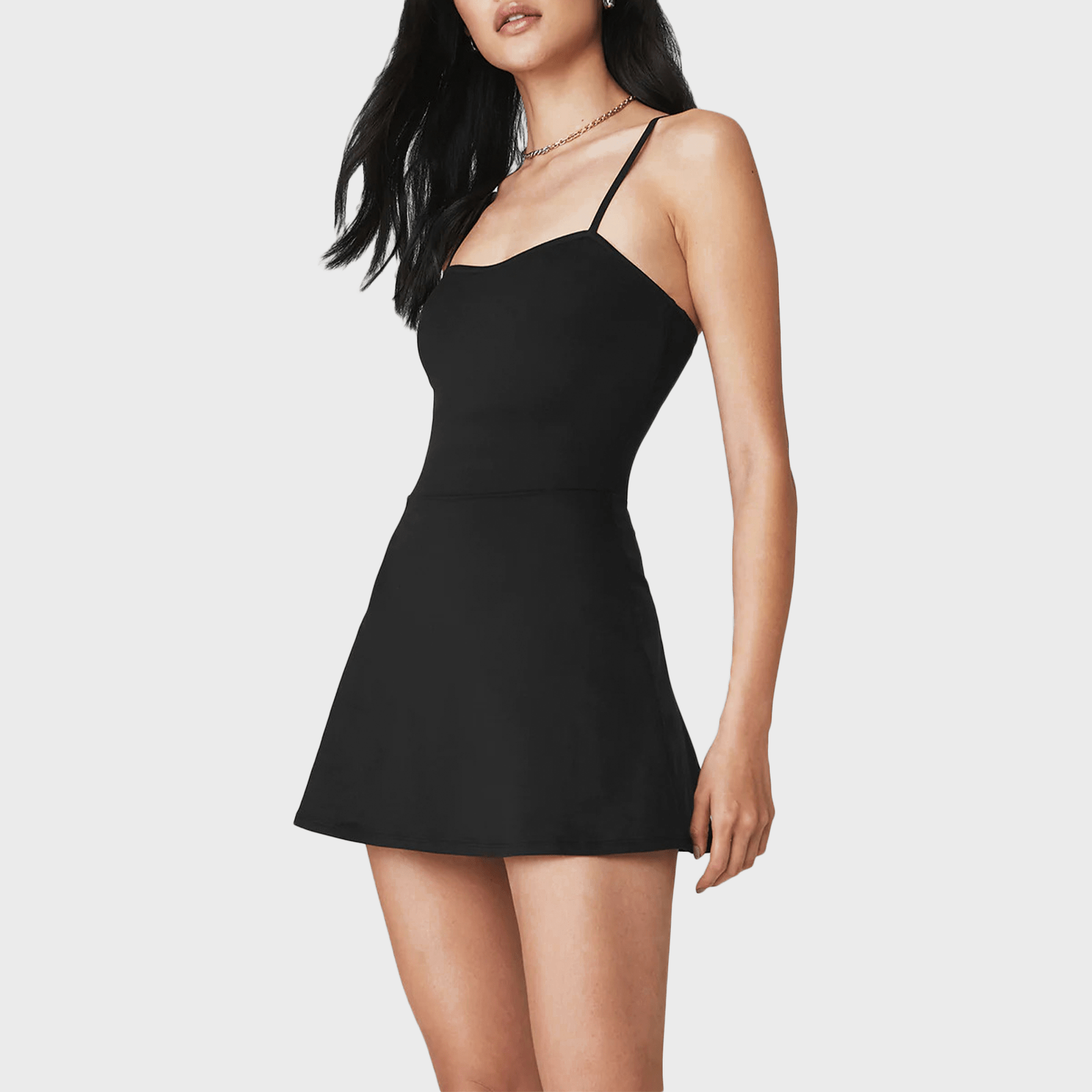 Woman wearing a black, sleeveless mini dress against a plain white background.