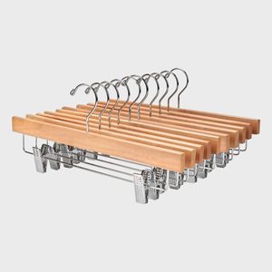 Wooden hangers with metal hooks are neatly arranged in a row, featuring clips for securing clothing, set against a plain white background.