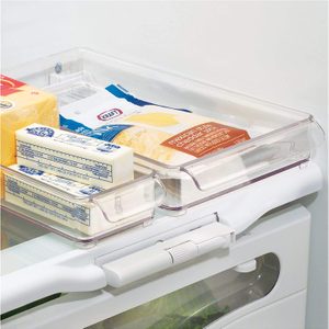 Transparent fridge drawer holds cheese and butter, stacked neatly, inside a refrigerator.