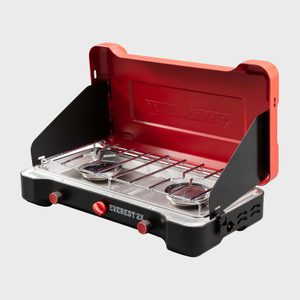 Portable camp stove set up with open lid, displaying two burners and a control panel, in a neutral studio environment. Text: 