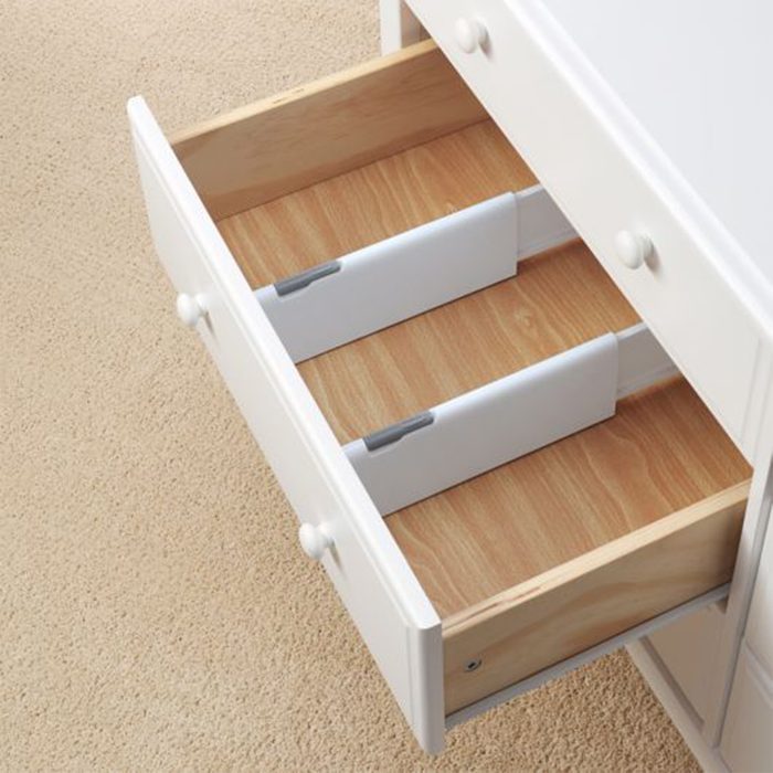 White drawers open, revealing wooden dividers inside, set against a beige carpeted floor.