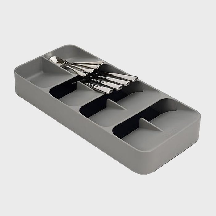 A gray utensil organizer holds several neatly stacked silver spoons in a kitchen setting.