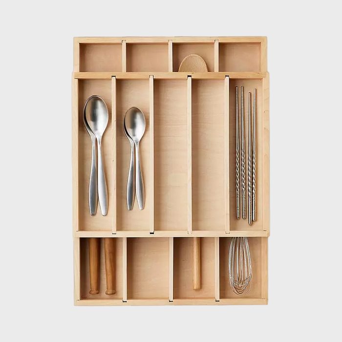 Wooden drawer organizer holds spoons, chopsticks, and utensils, neatly arranged in compartments against a plain background.