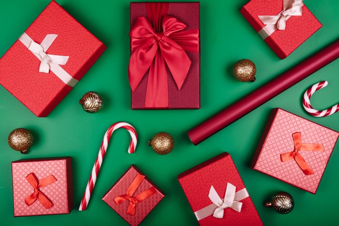Christmas background with gift boxes, clews of rope, paper's rools and decorations on red. Preparation for holidays. Top view with copy space.