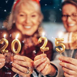 Hands holding lit gold candles shaped as 